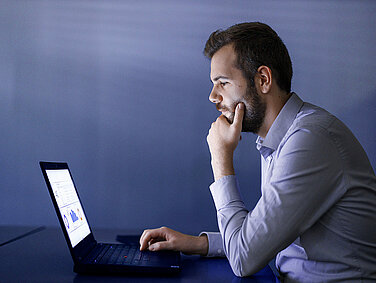 A Leadec employee sits in front of a laptop in a darkened room.