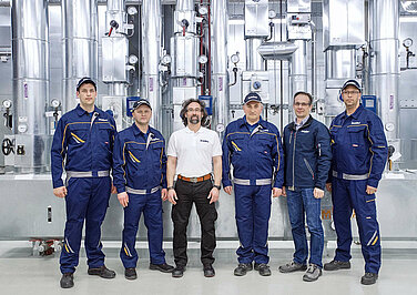 A group of Leadec employees in front of a compressor unit. 
